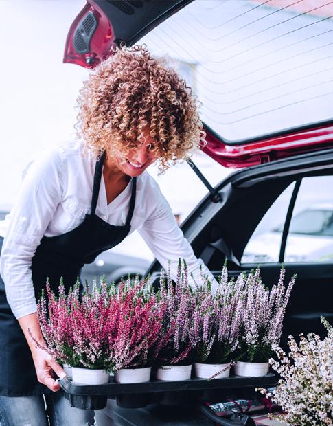Women unpacking car with Spring flowers - Agero