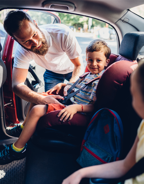 Dad Putting kids in Car Seat - Agero
