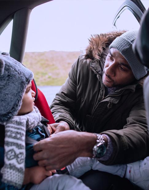 Agero - Dad putting seat belt on 6 month old child